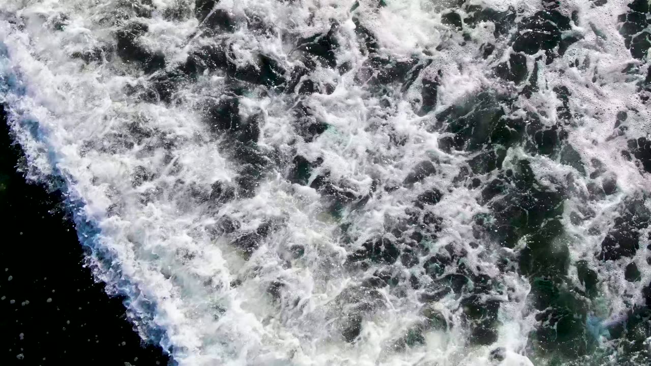 White foam spreading across dark green seawater