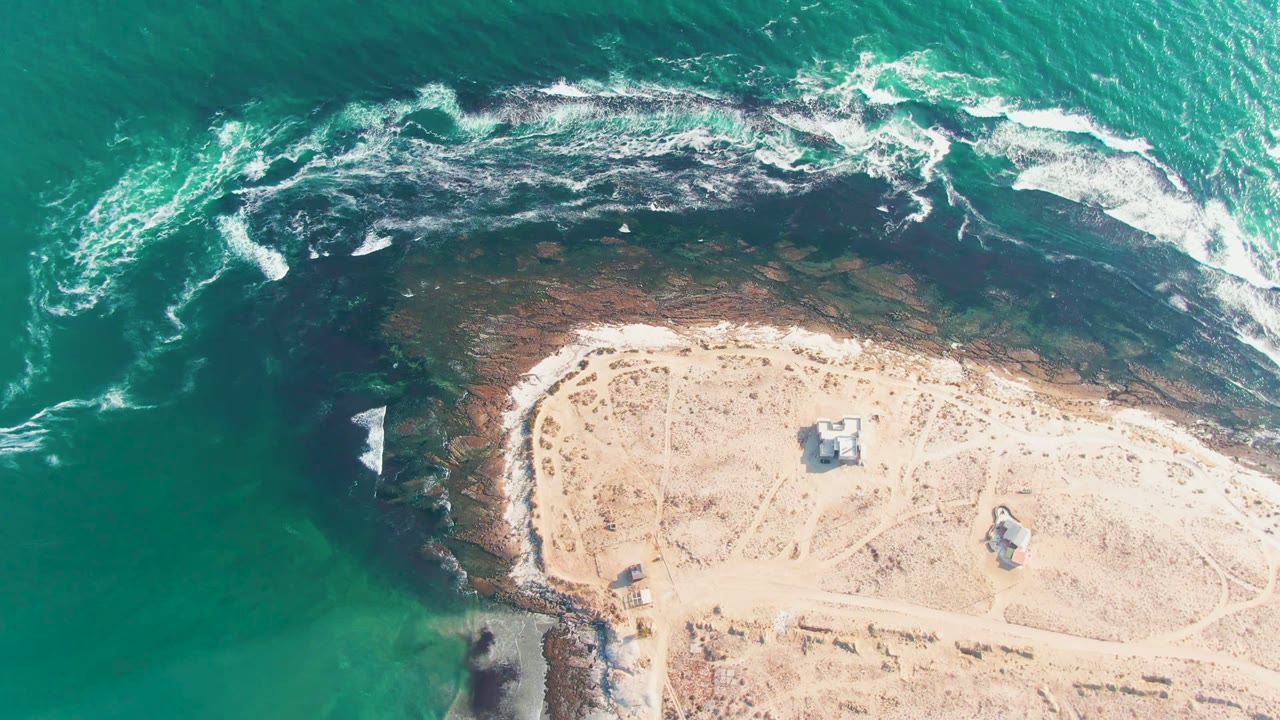 Top-down coastal view with white foam curling along the island shore.