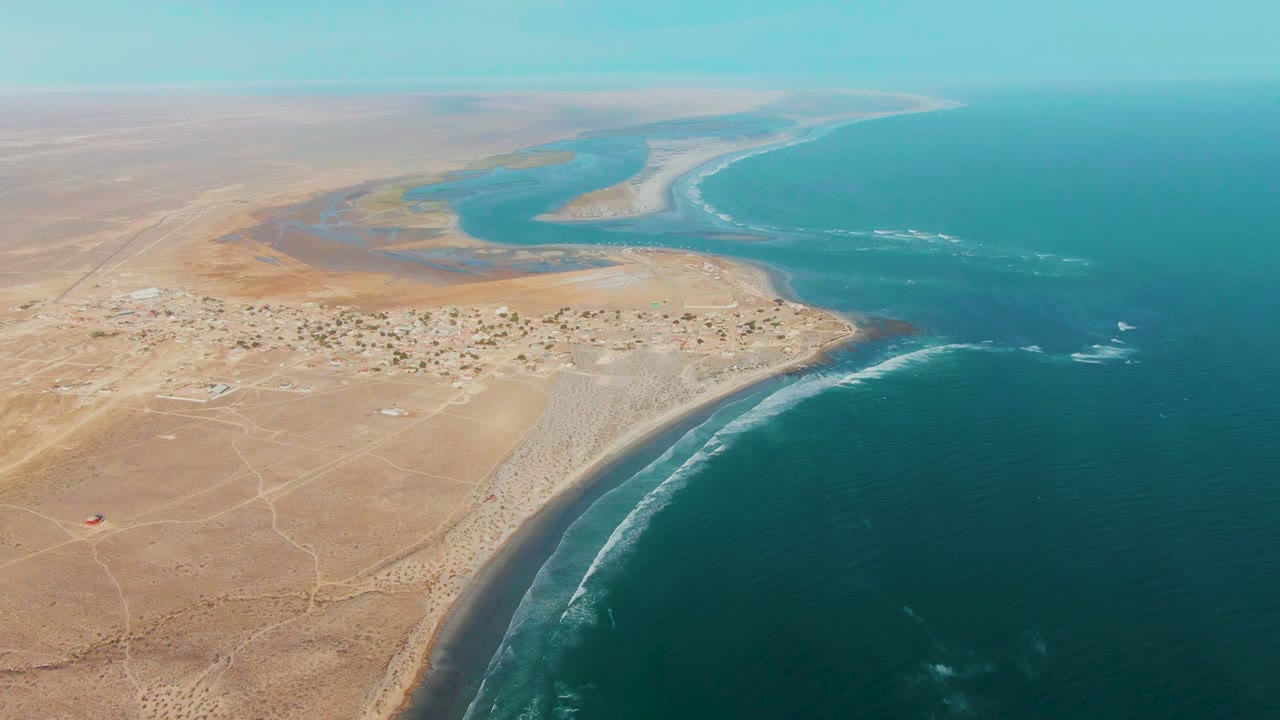 Wide drone view of sandy coast with lagoon and blue ocean.