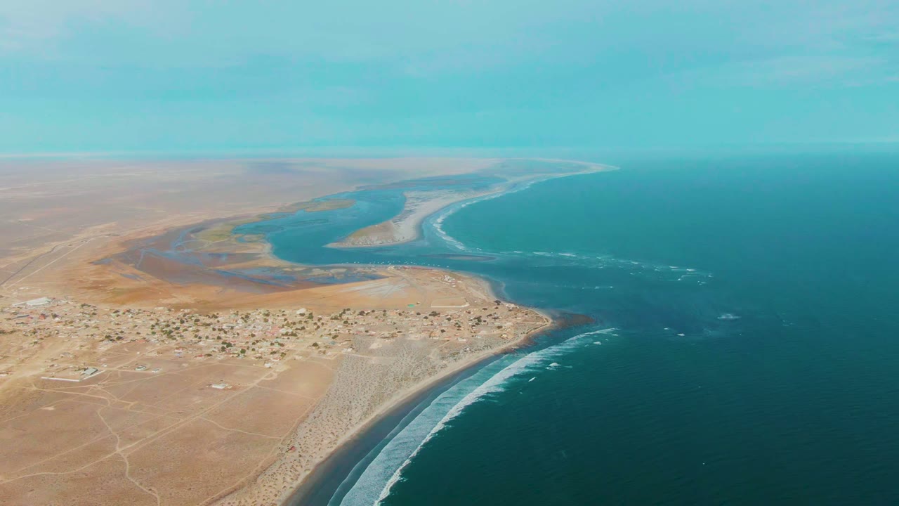 Wide aerial view of La Bocana coastline with estuary water and surf.