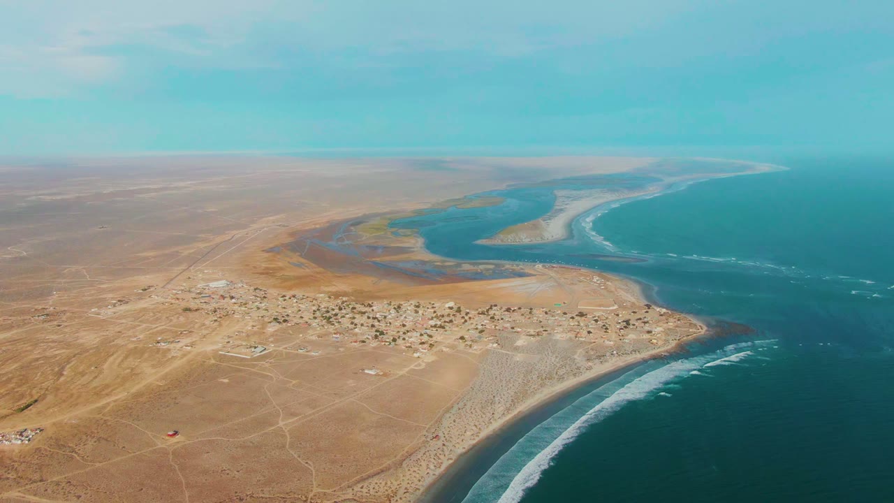 Coastal desert village with surf and blue water from above