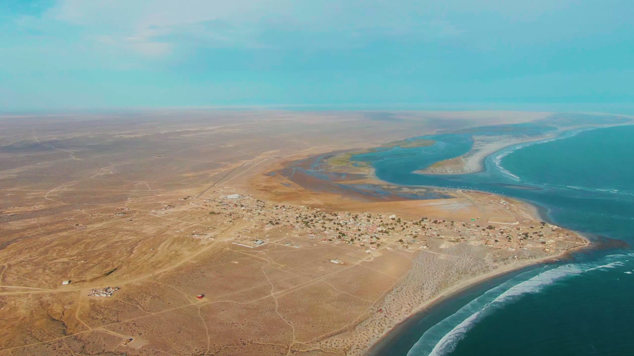 Aerial coastal landscape with desert tracks, settlement, lagoon, and ocean.