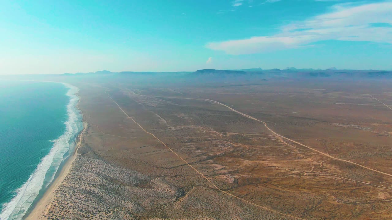 Wide aerial view of surf line, beach, and desert road grid