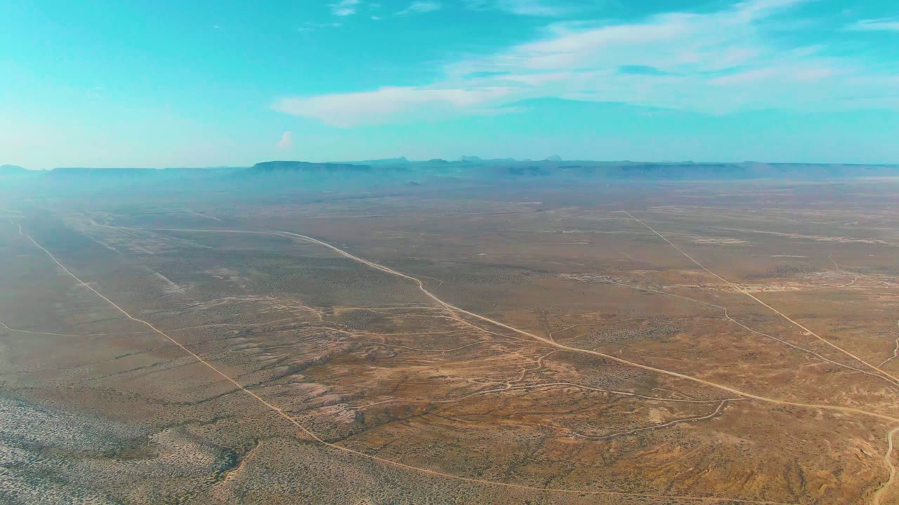 Wide desert aerial with pale roads cutting across open scrubland.