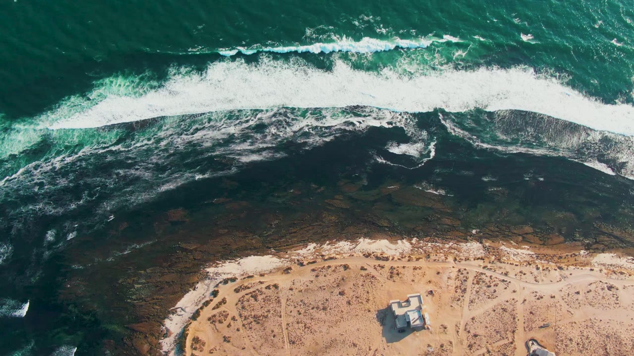 White surf rolling toward a tan beach from above