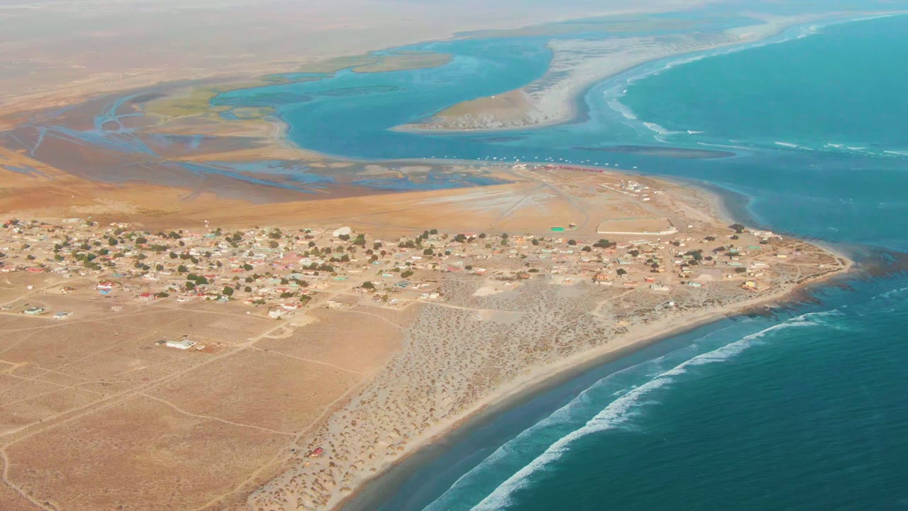Desert shoreline village with surf and lagoon from above
