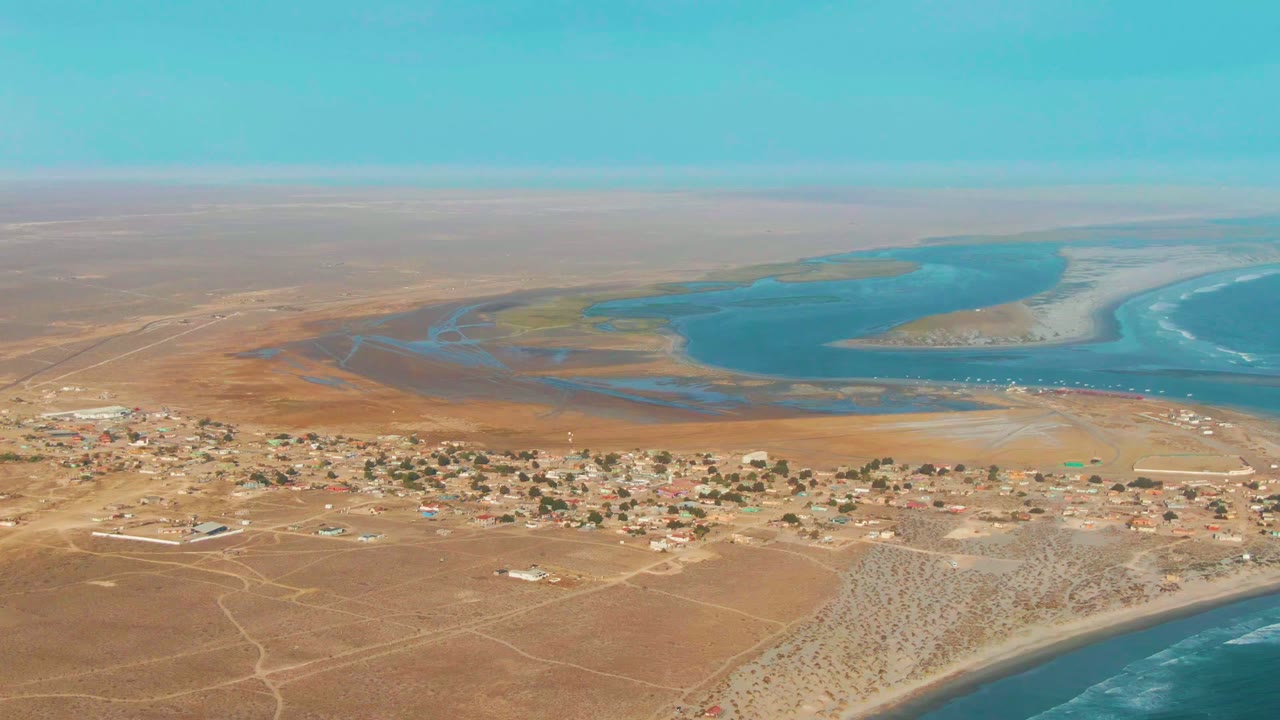 High aerial view over sandy settlement and blue lagoon