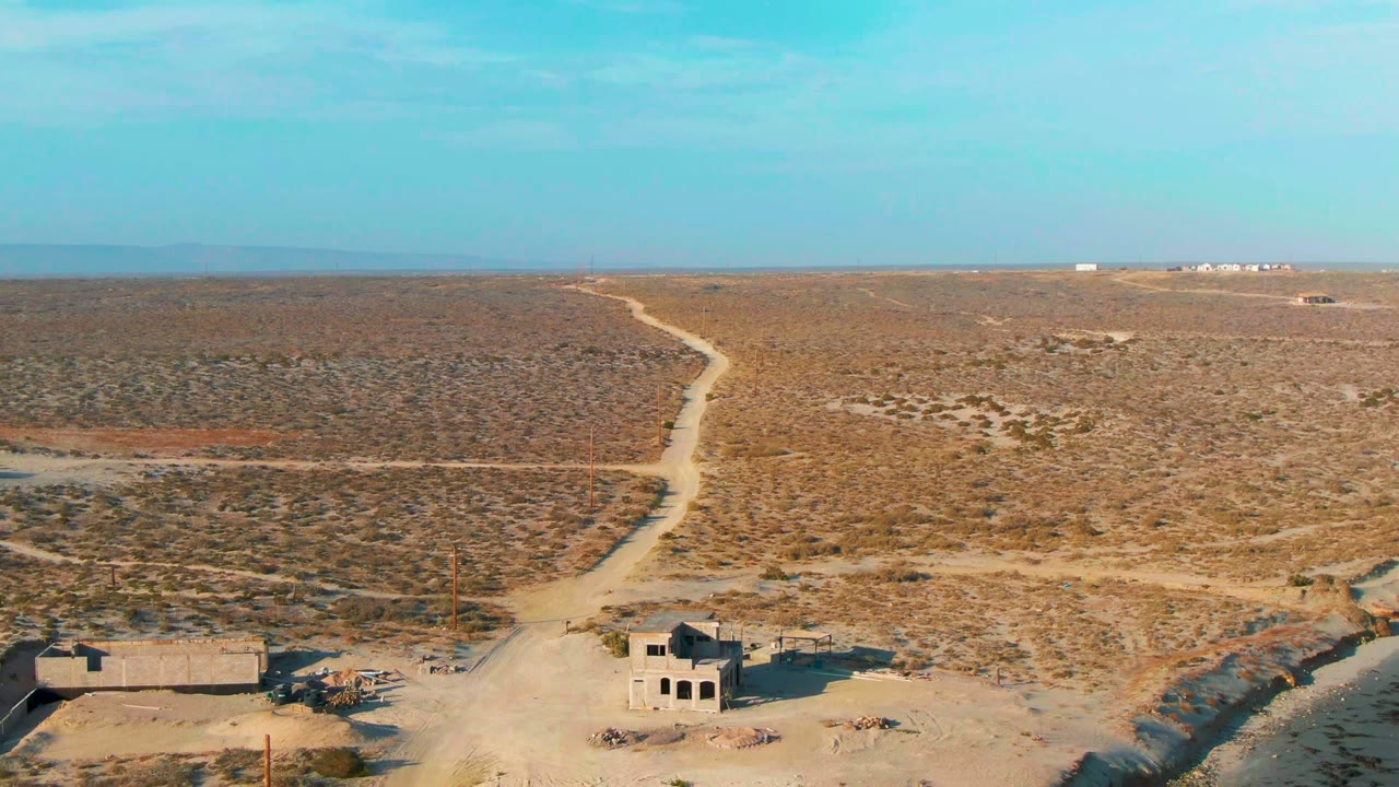 Desert road leading past small abandoned structures
