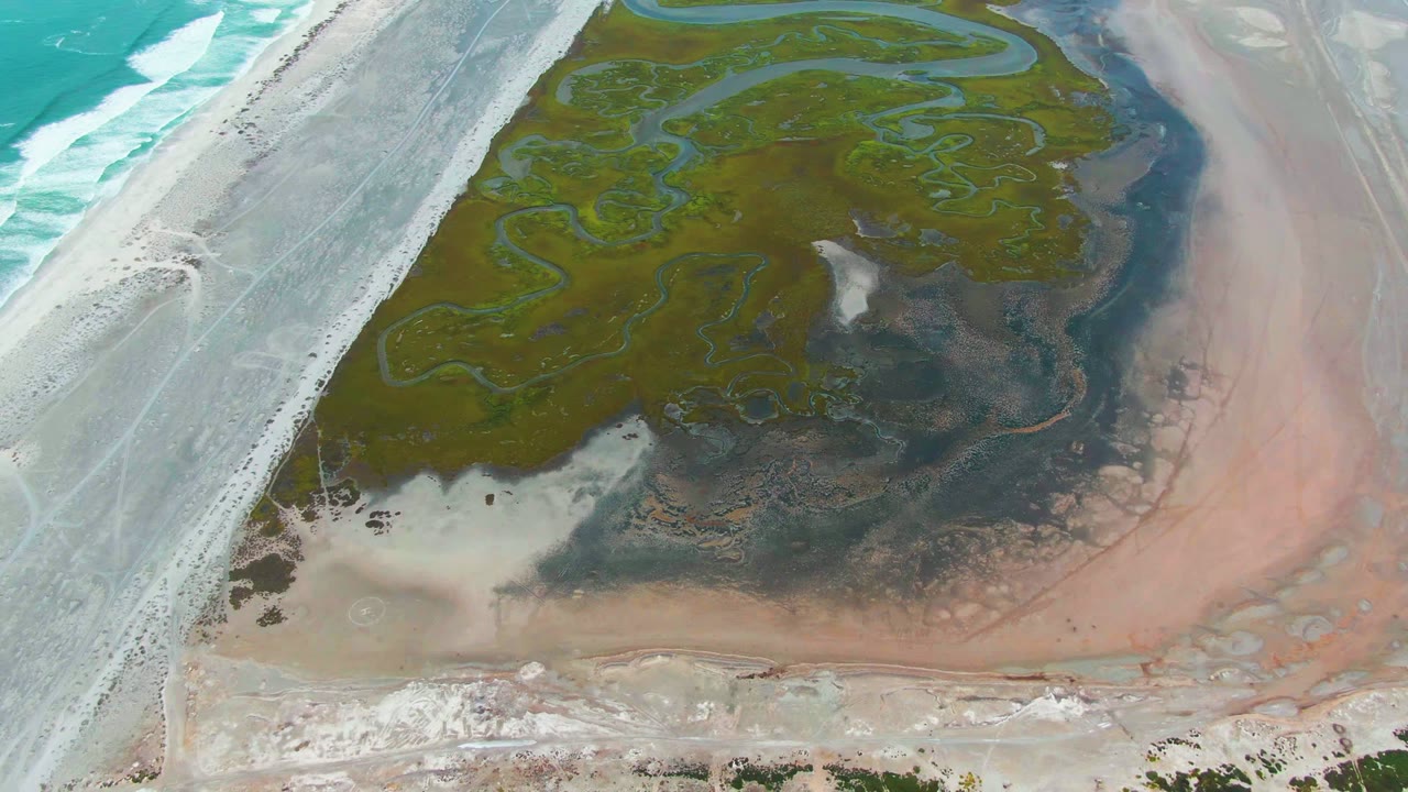 Overhead lagoon with green algae channels beside surf and pale shallow water.