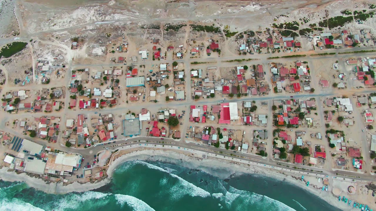 Aerial view of houses, shore road, and breaking waves
