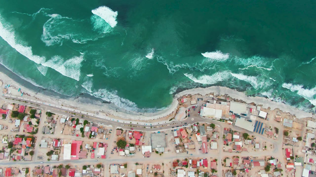 Coastal road and houses below active whitewater surf.