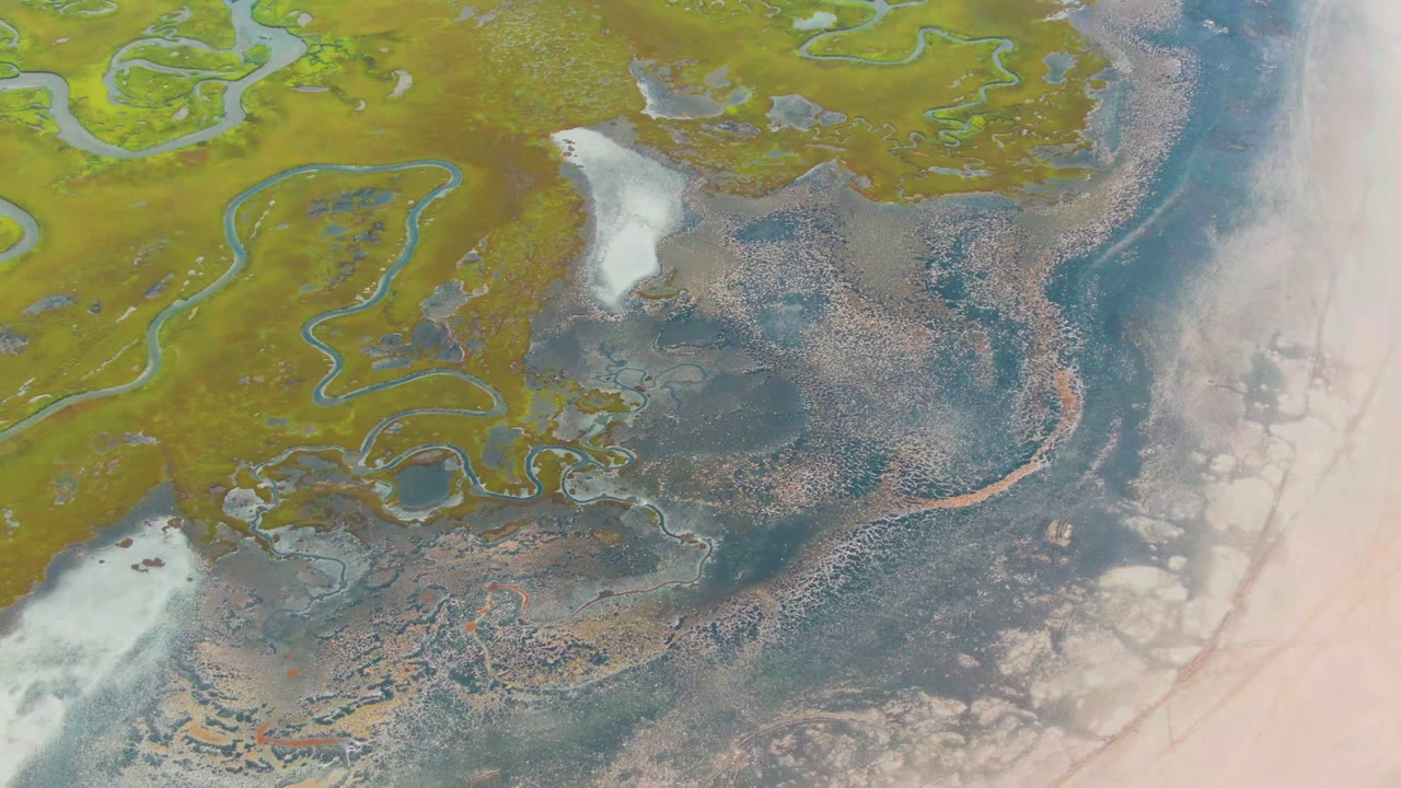 At two seconds, the Punta Abreojos frame shows meandering water channels across green marsh, a white cloud or bright haze area near the lower left, dark tidal pools in the middle, and no visible people.