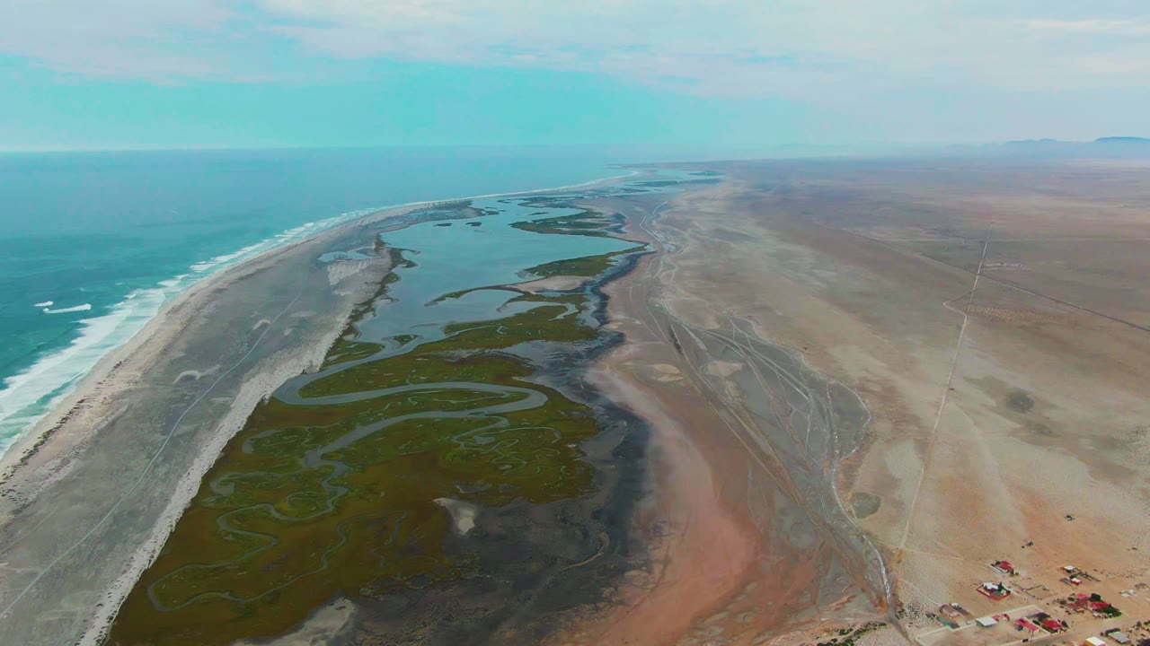 Wide coastal aerial with lagoon channels beside the ocean and desert.