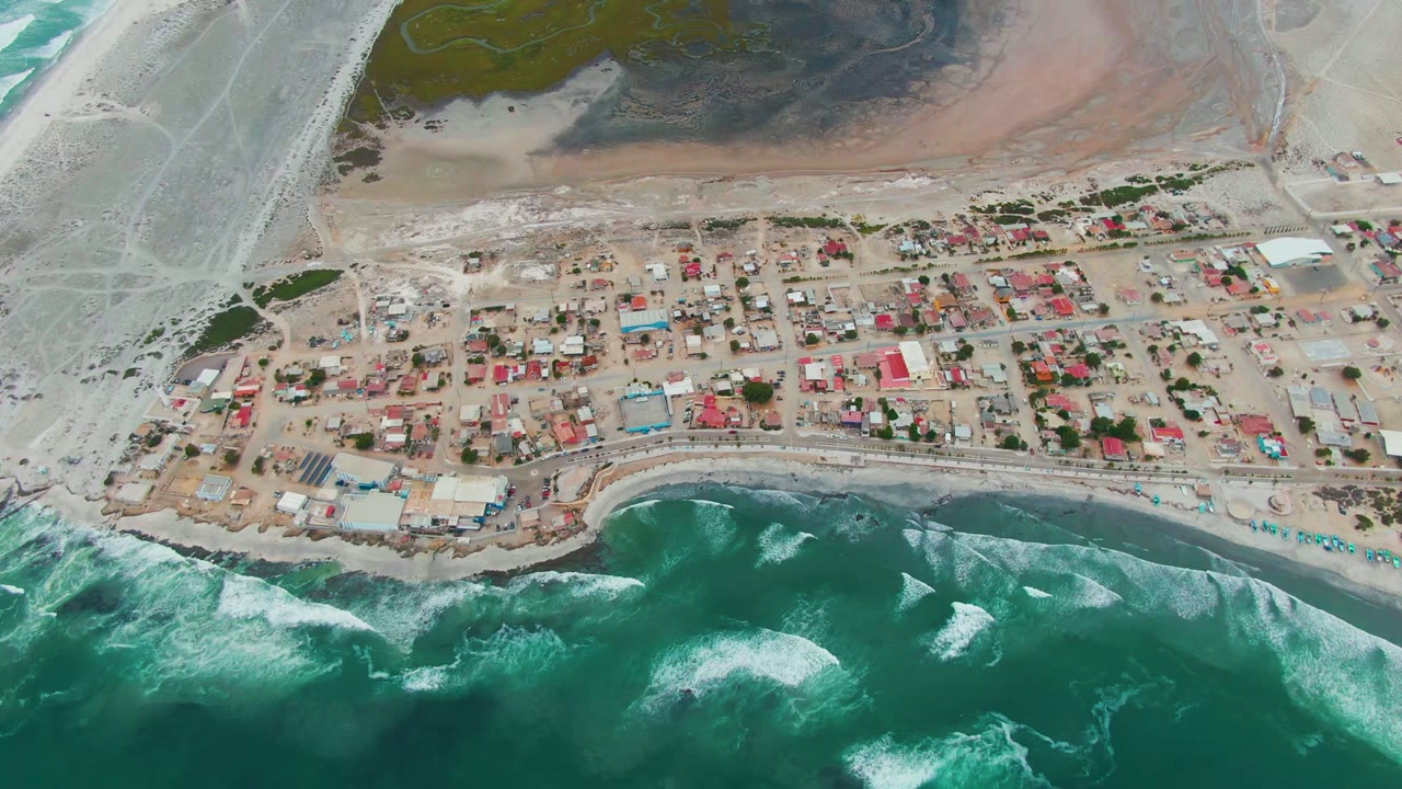 Aerial village grid with surf breaking along the lower shoreline.