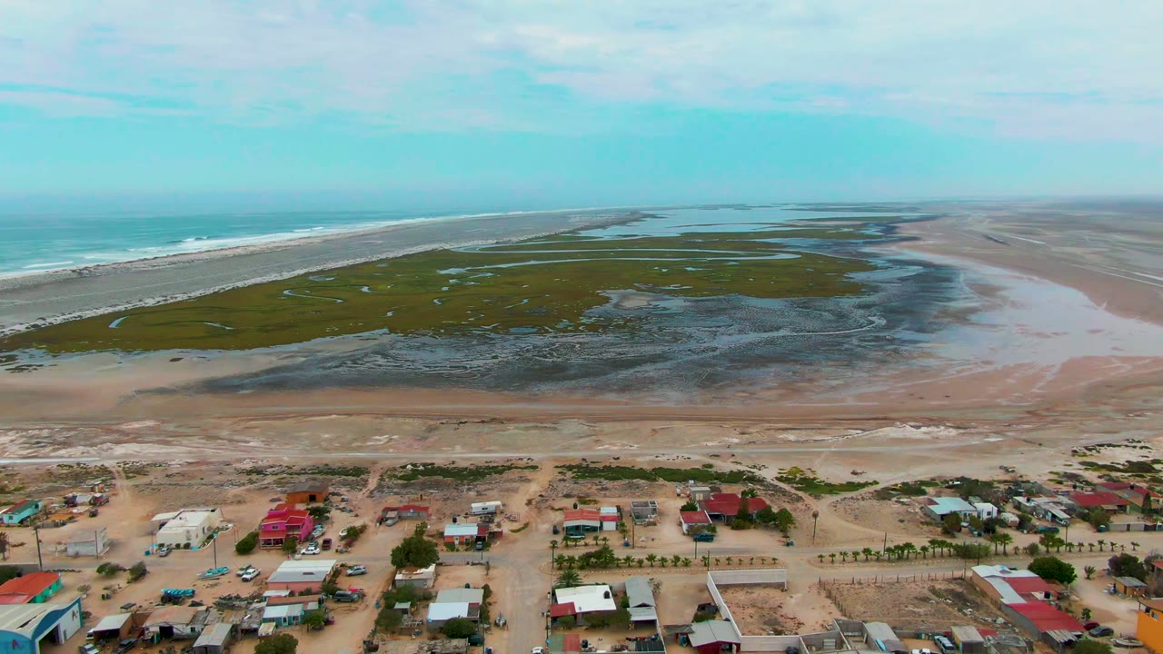 Coastal houses and roads below marsh flats, beach, and ocean
