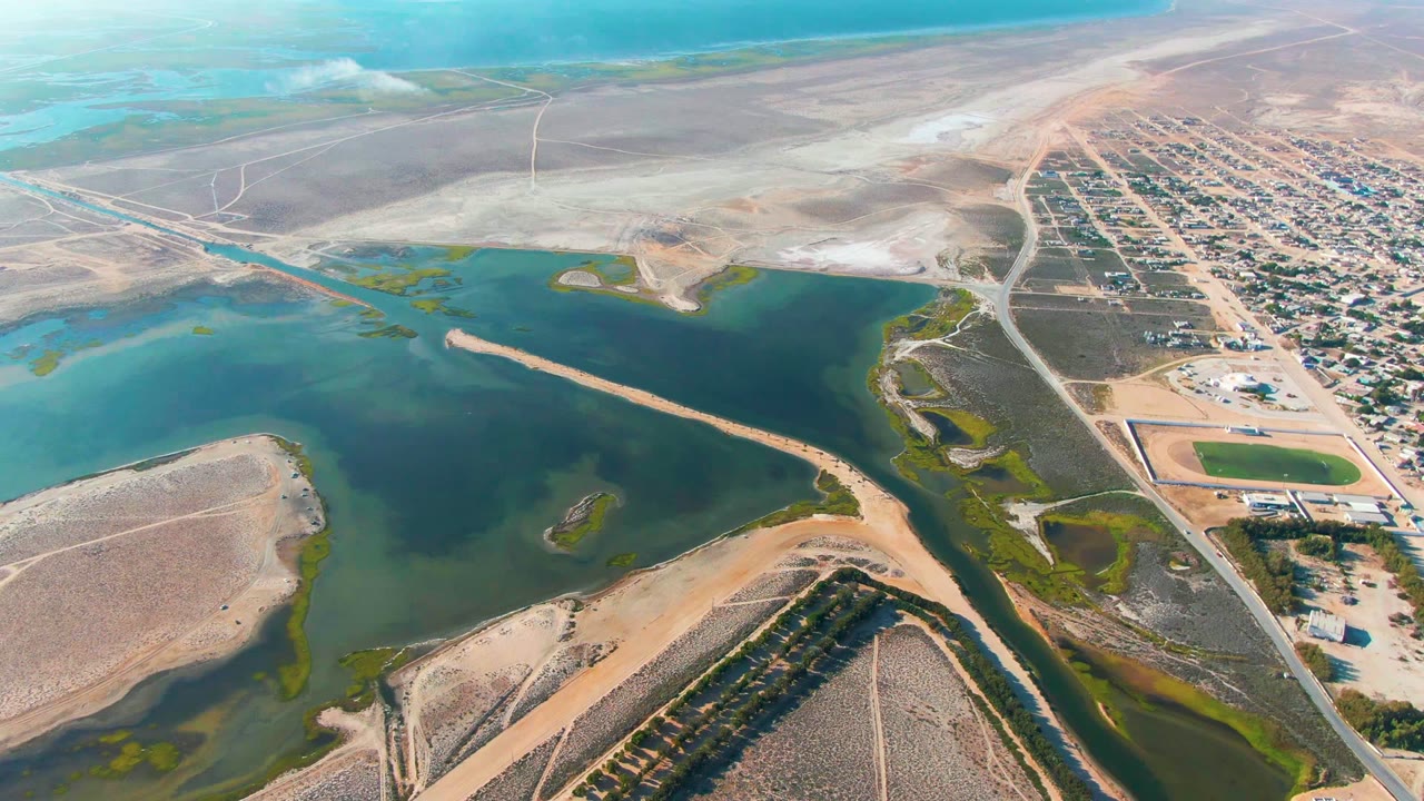 Drone view of inland water with a dark cloud shadow and nearby development.