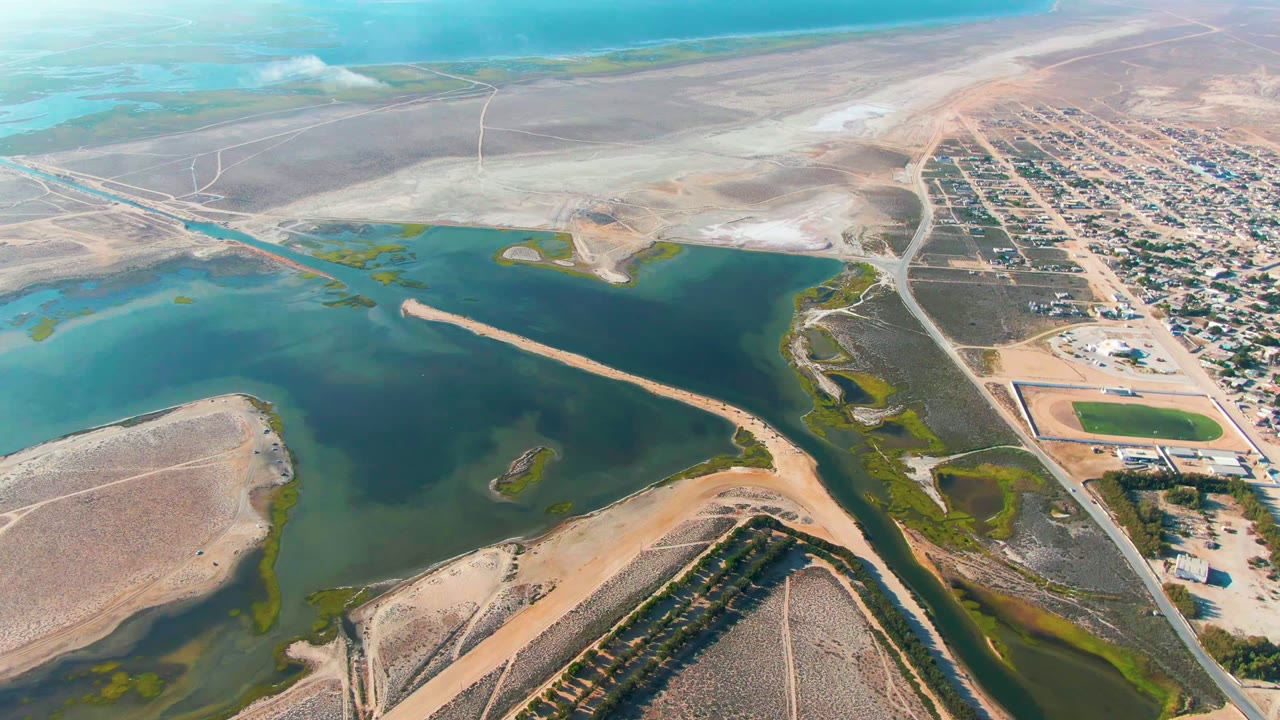At two seconds, the elevated view over Guerrero Negro holds on turquoise water, a long sandy strip, desert flats, town blocks, and no visible people.