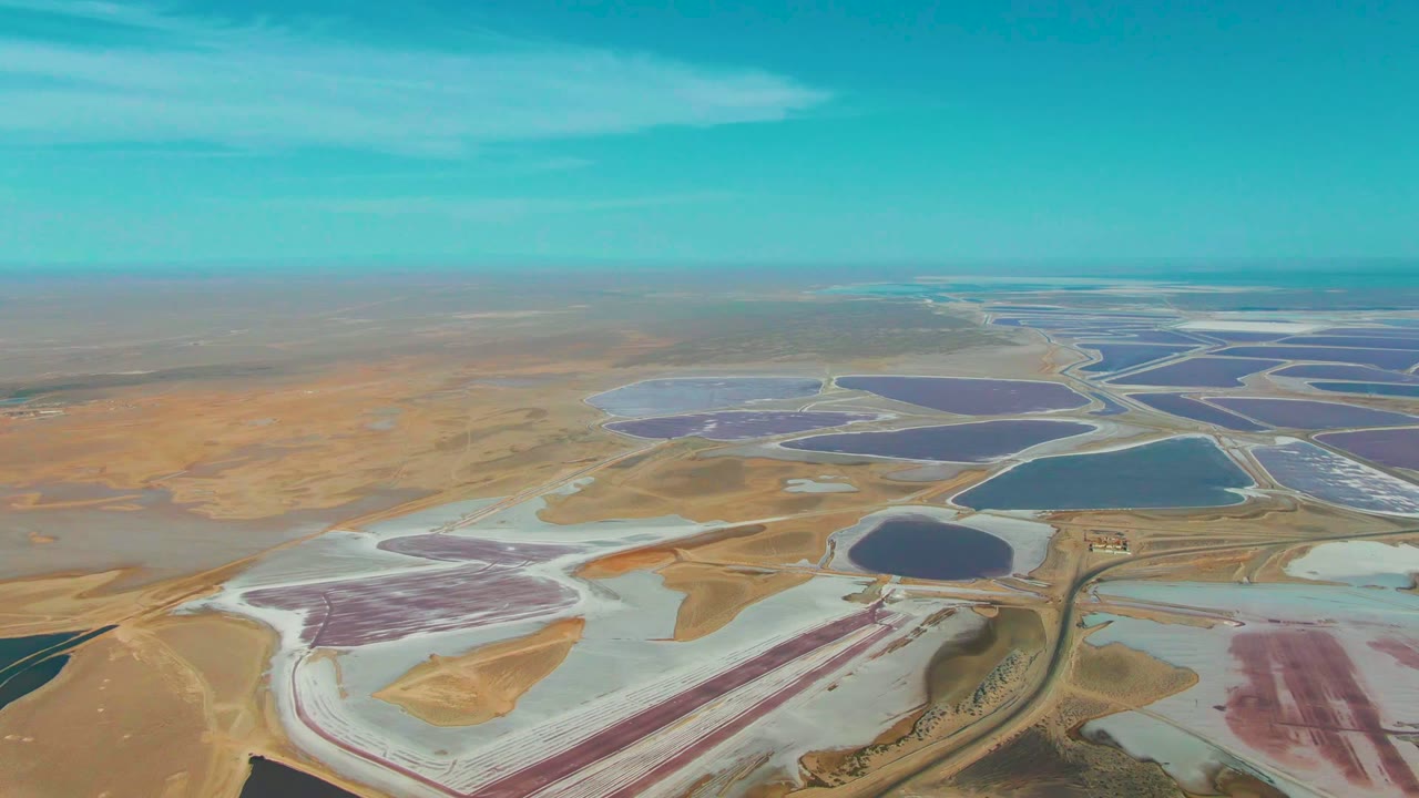Drone view across pink, purple, and blue salt ponds.