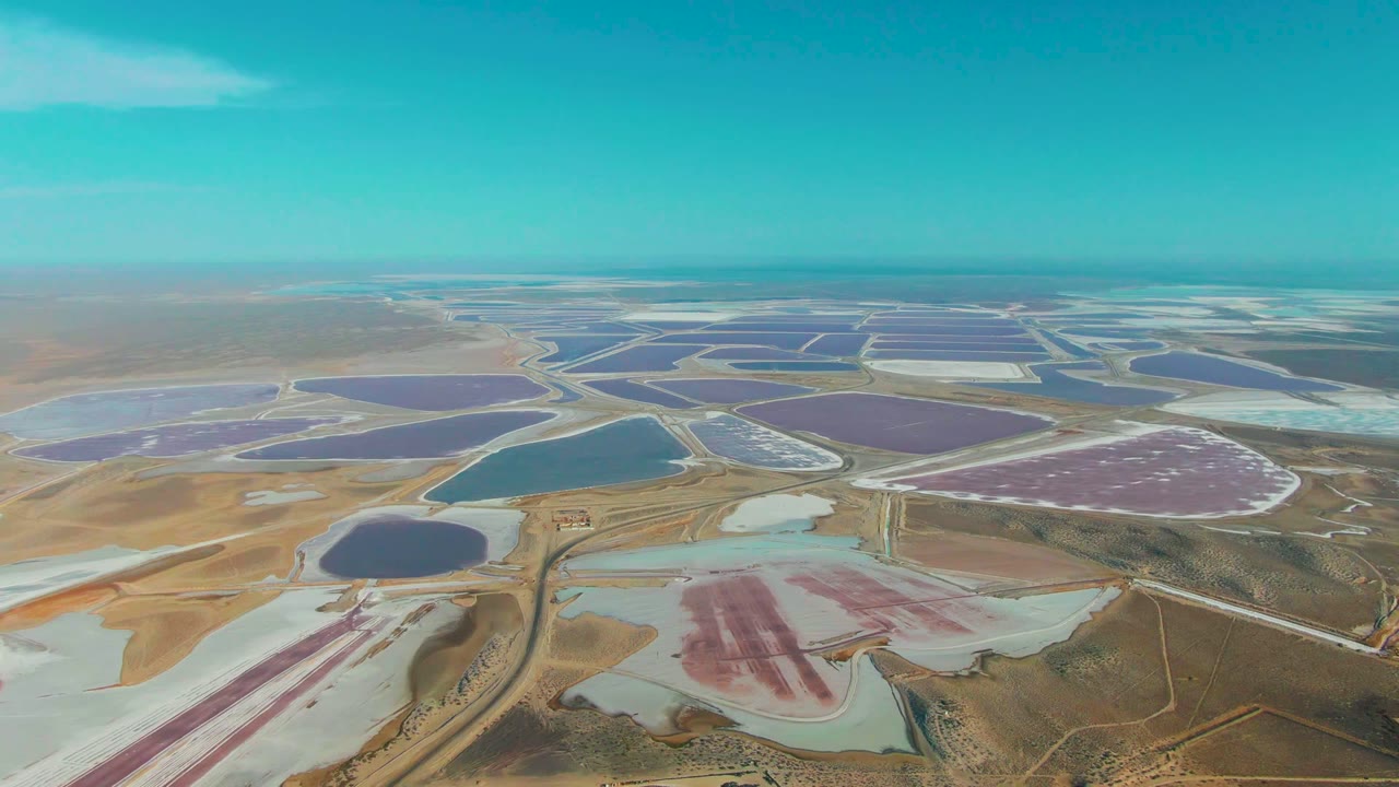 High aerial view of salt ponds, service roads, and arid land.