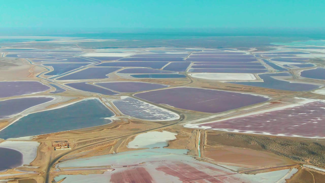 Aerial salt ponds with purple basins, blue water, and pale salt flats.
