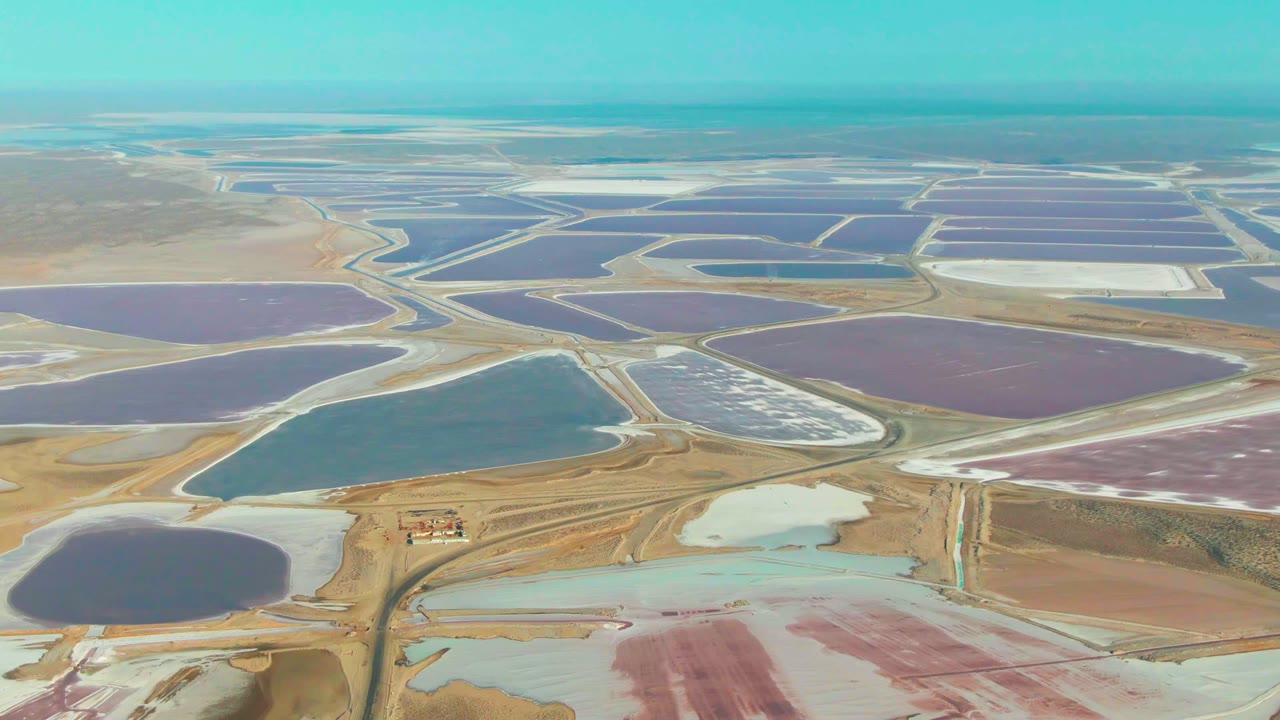 Drone-height view across geometric salt ponds and pale salt flats.