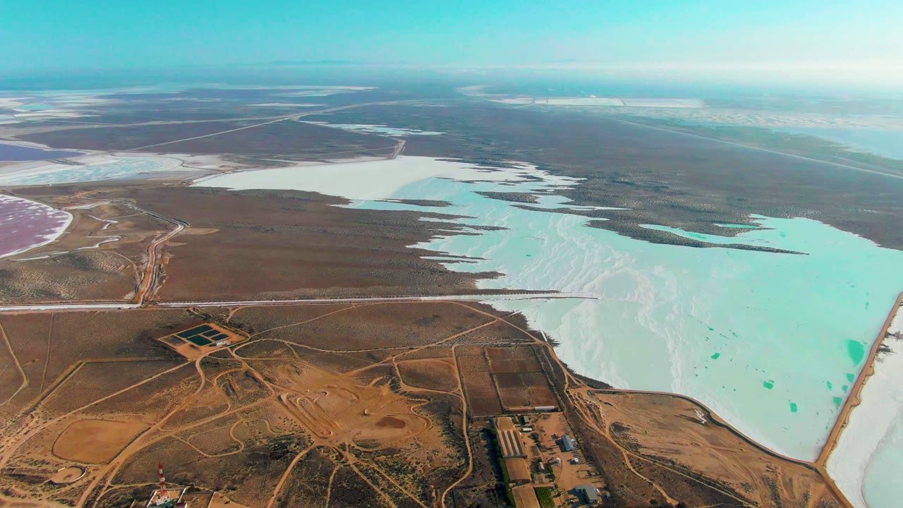 Drone view of salt lakes, dry land, roads, and small foreground structures