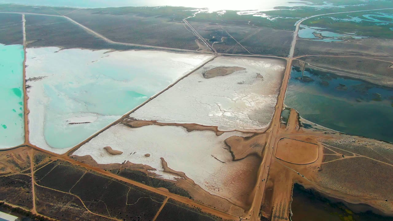 Salt ponds with a diagonal dike crossing pale water and darker basins.