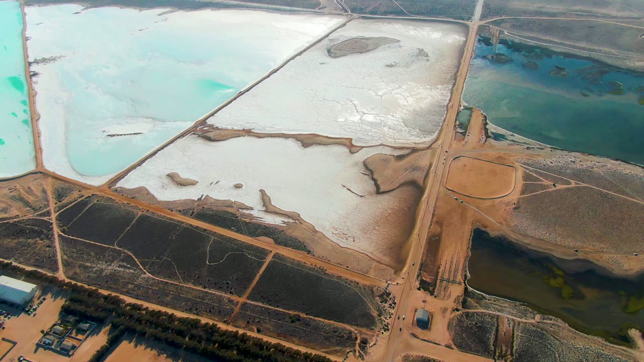 Aerial salt ponds with pale white flats and blue water basins.