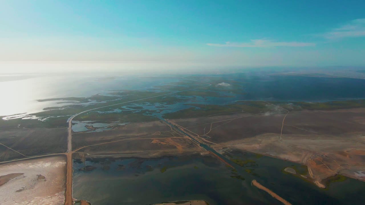 High aerial view of roads crossing wetlands and brown coastal terrain.