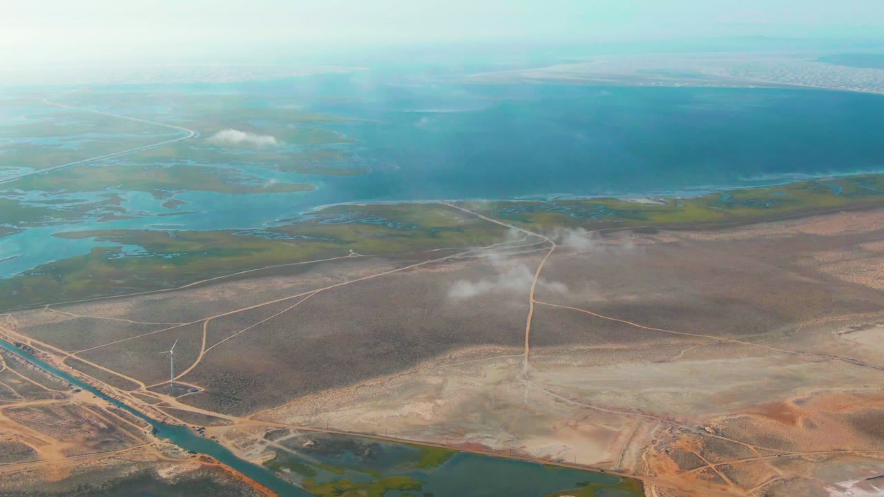 Third frame shows the Guerrero Negro aerial composition with the mist plume stretched over muted brown land, straight and curving roads below, blue-green wetland patches to the left, and no visible people.