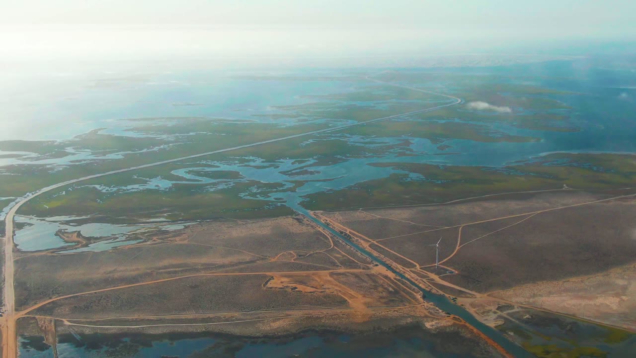 High aerial view of wetland channels, road lines, and open marshland.