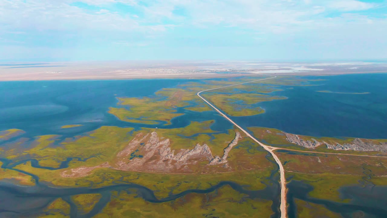 Drone view of road curving between wetlands and open water