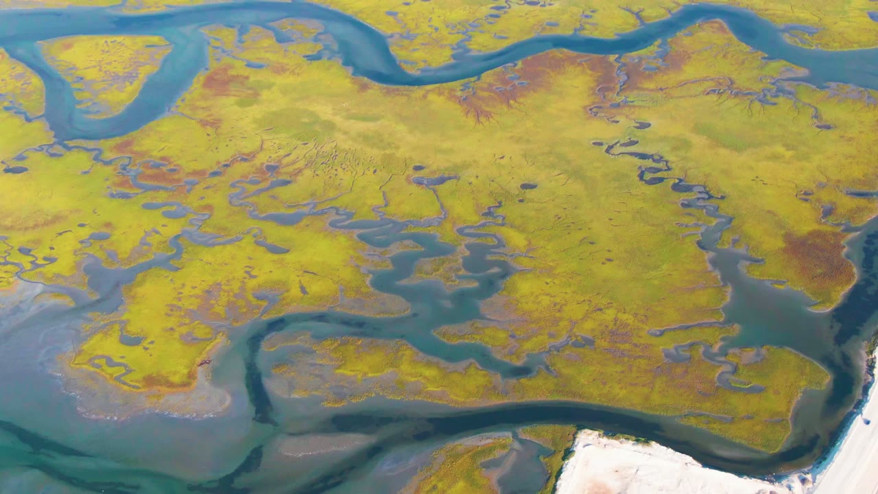 Overhead wetland channels and marsh islands with pale shoreline below.