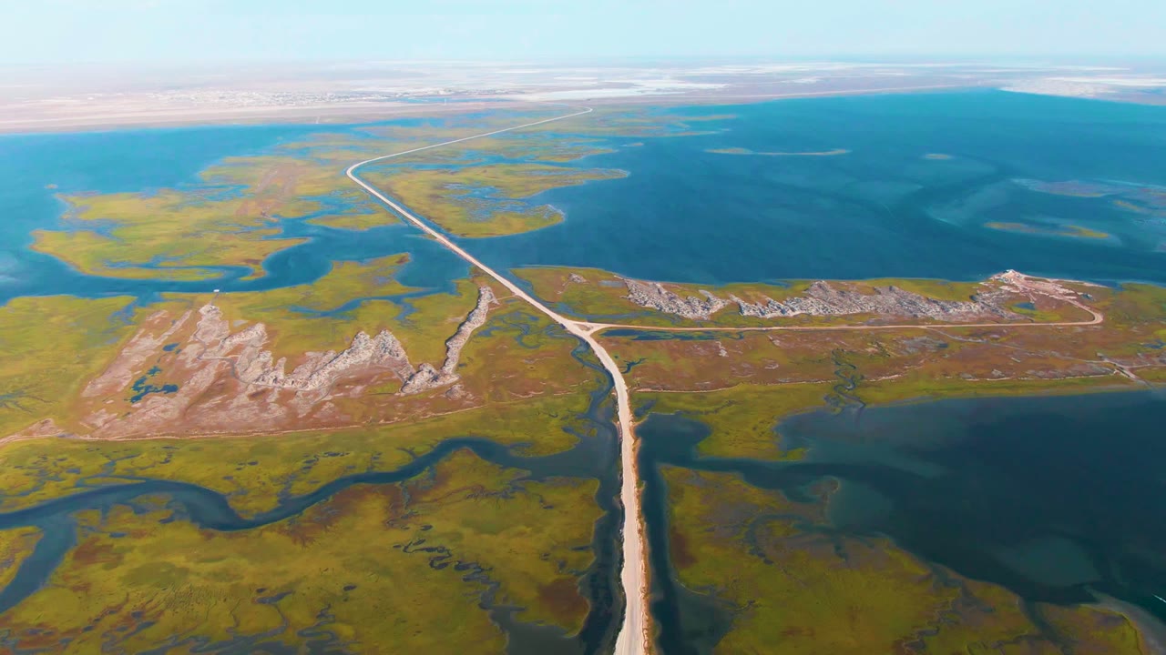 Aerial road and causeway running between marsh channels and blue lagoon water.