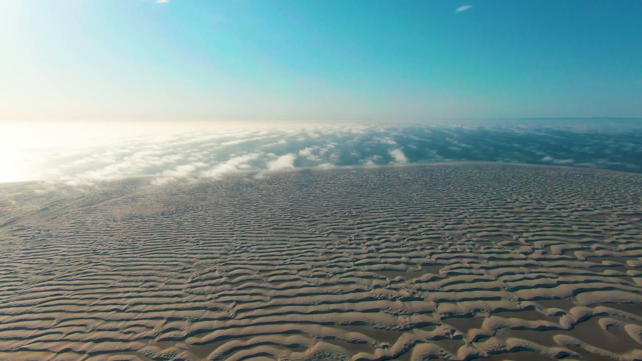 Textured cloud field stretches toward a hazy horizon under blue sky.