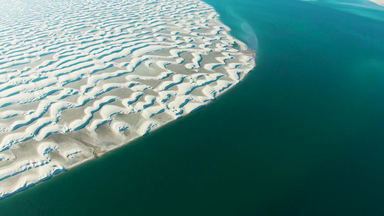 White dune ridges curving along green-blue coastal water