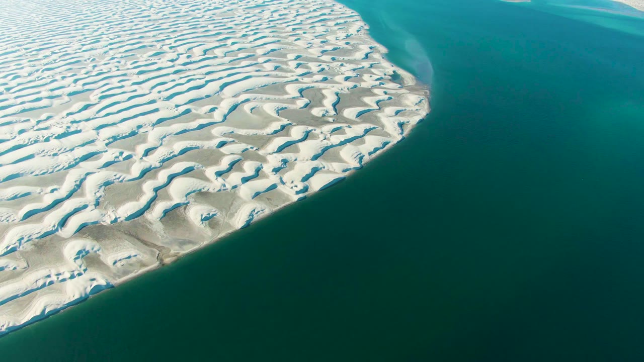 At 0:00, rippled white sand dunes in Guerrero Negro curve beside turquoise ocean water, with no visible people.