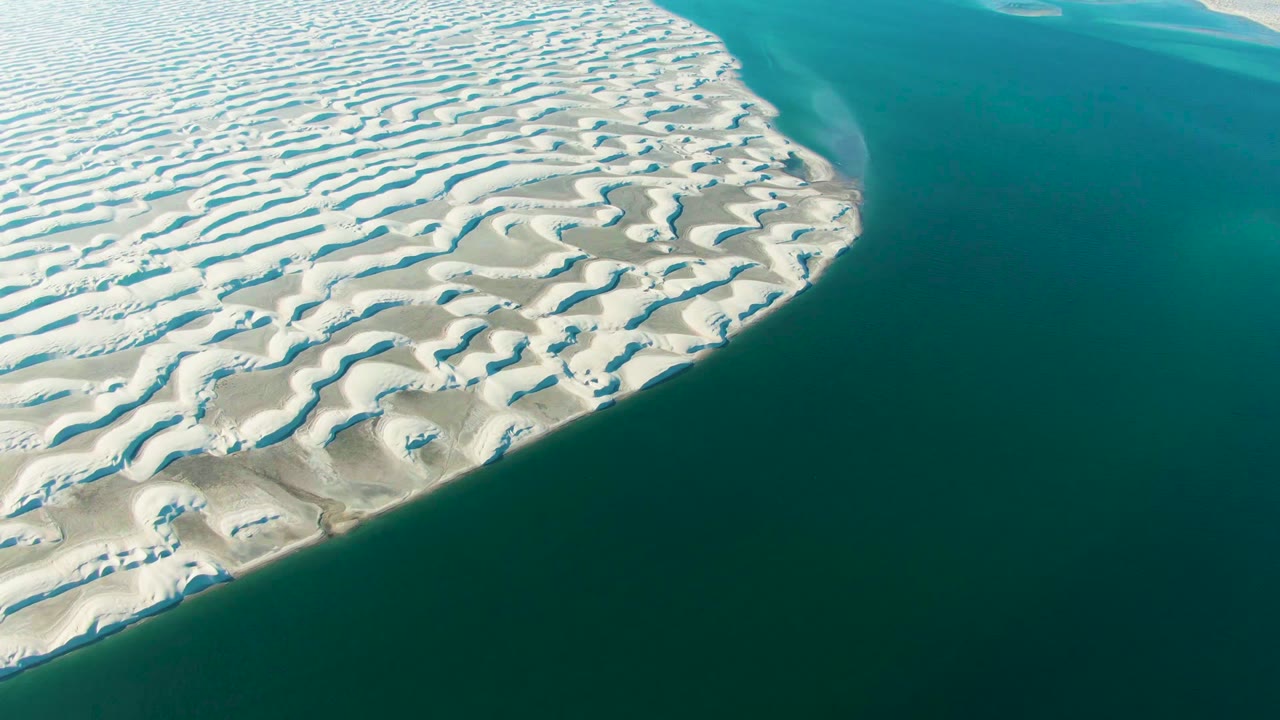 At 0:02, the curved Guerrero Negro sand edge meets darker turquoise water, with the dune ridges visible across the left half and no visible people.