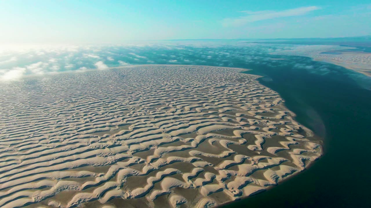 Patterned sand ridges curving toward ocean water