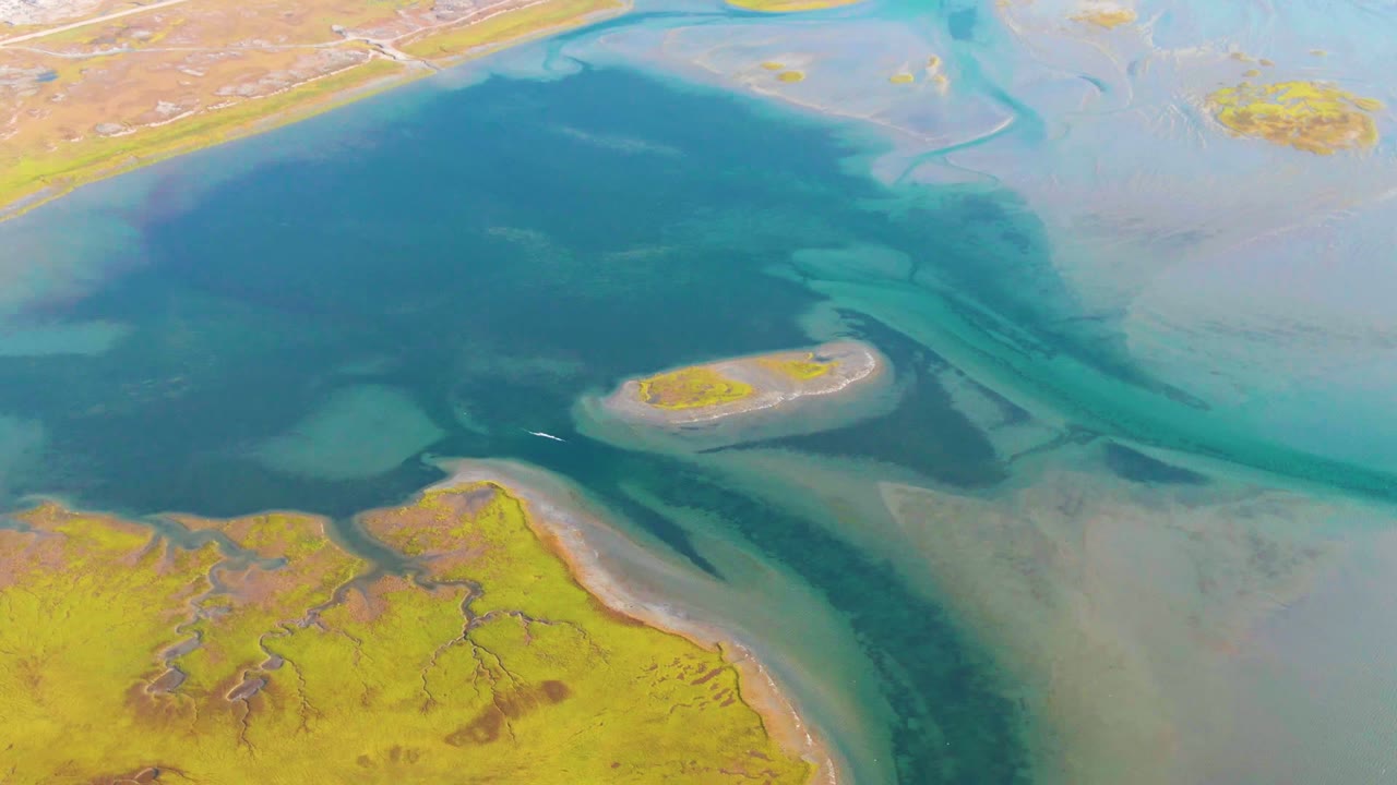 Drone view of blue water around a small marsh island