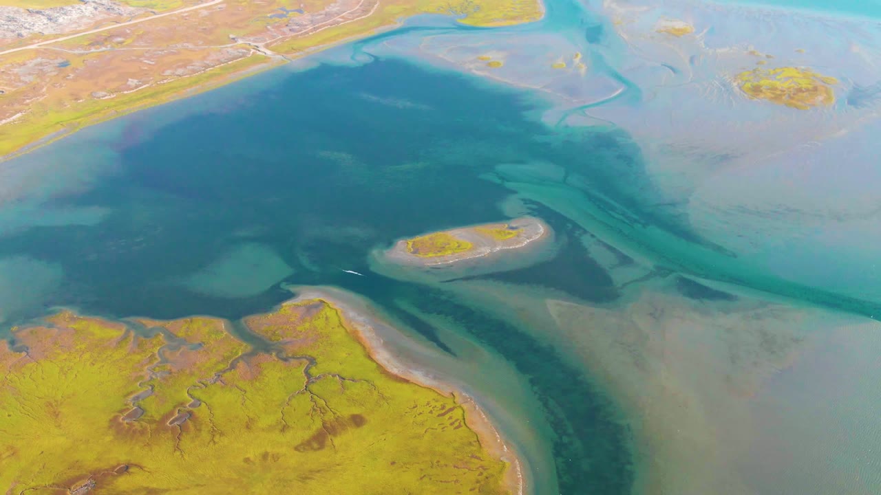 Aerial footage over Guerrero Negro shows the central water basin, pale turquoise shallows, a narrow sandbar edge, yellow marsh below, and no visible people.