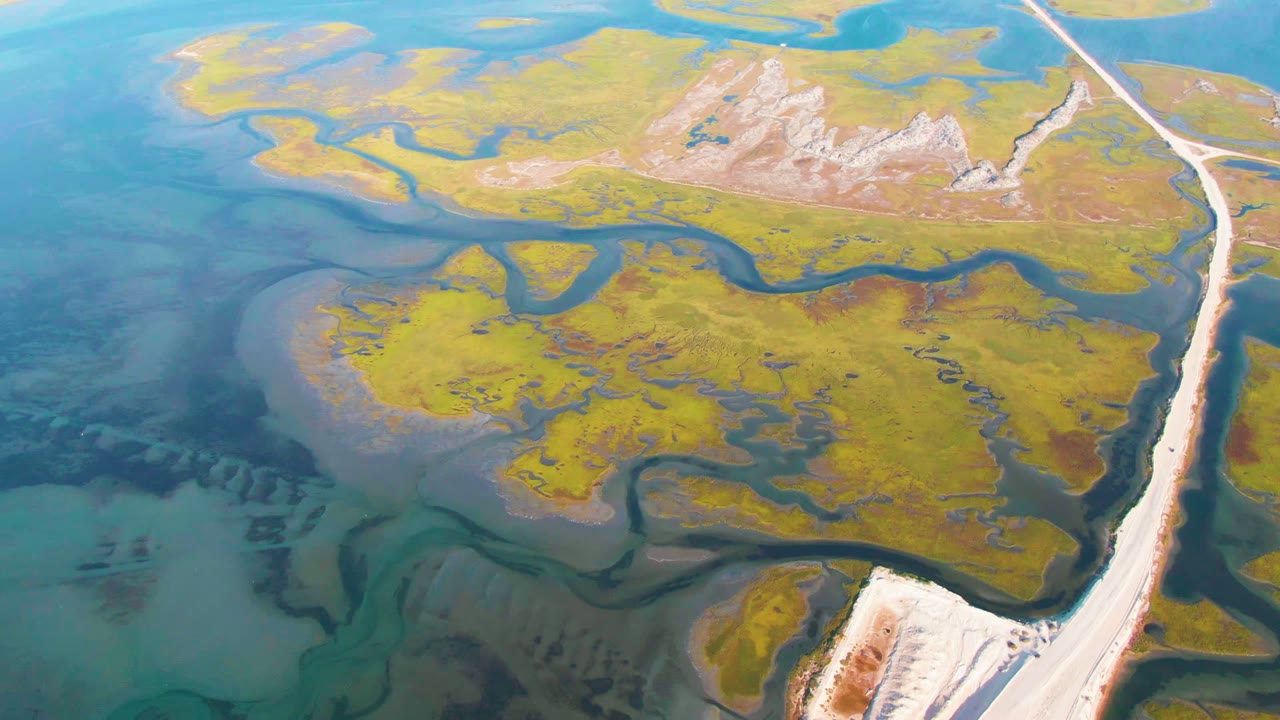 Drone view of green marsh islands cut by blue water channels
