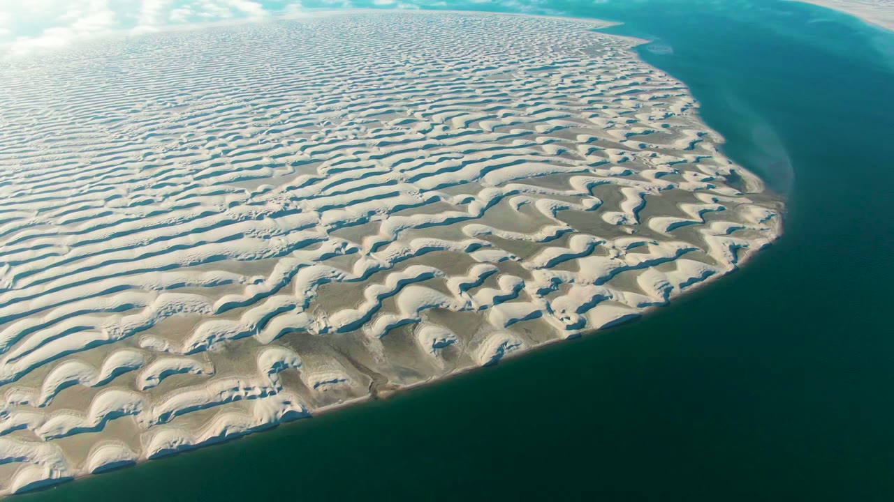 Patterned coastal sand with blue water along the right side