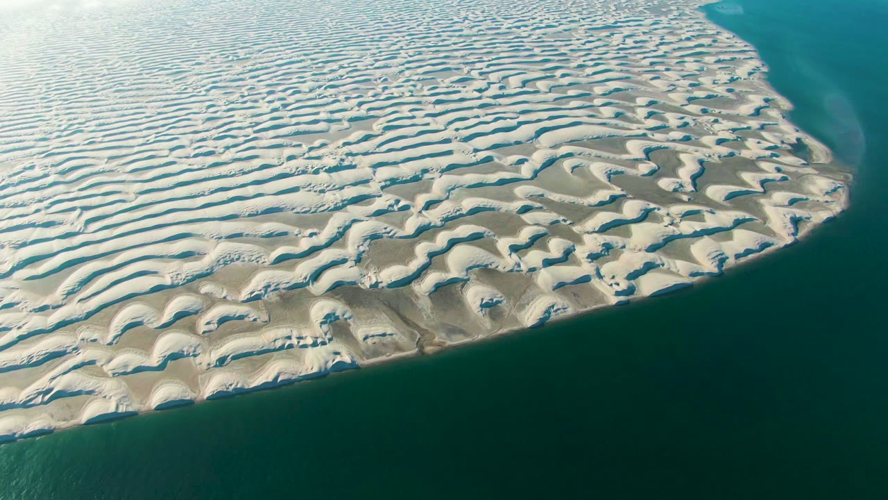 Rippled sand flats and dune ridges border dark coastal water.