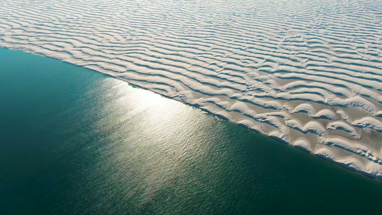 White dune ridges border calm blue-green ocean water.