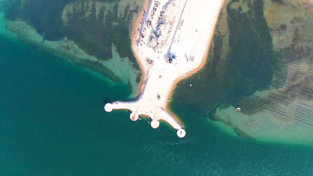 Aerial view of circular pier ends over green coastal water