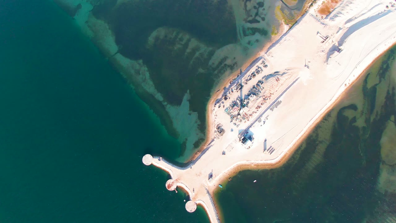 Aerial view of the causeway angled across teal water with exposed pale shoreline.