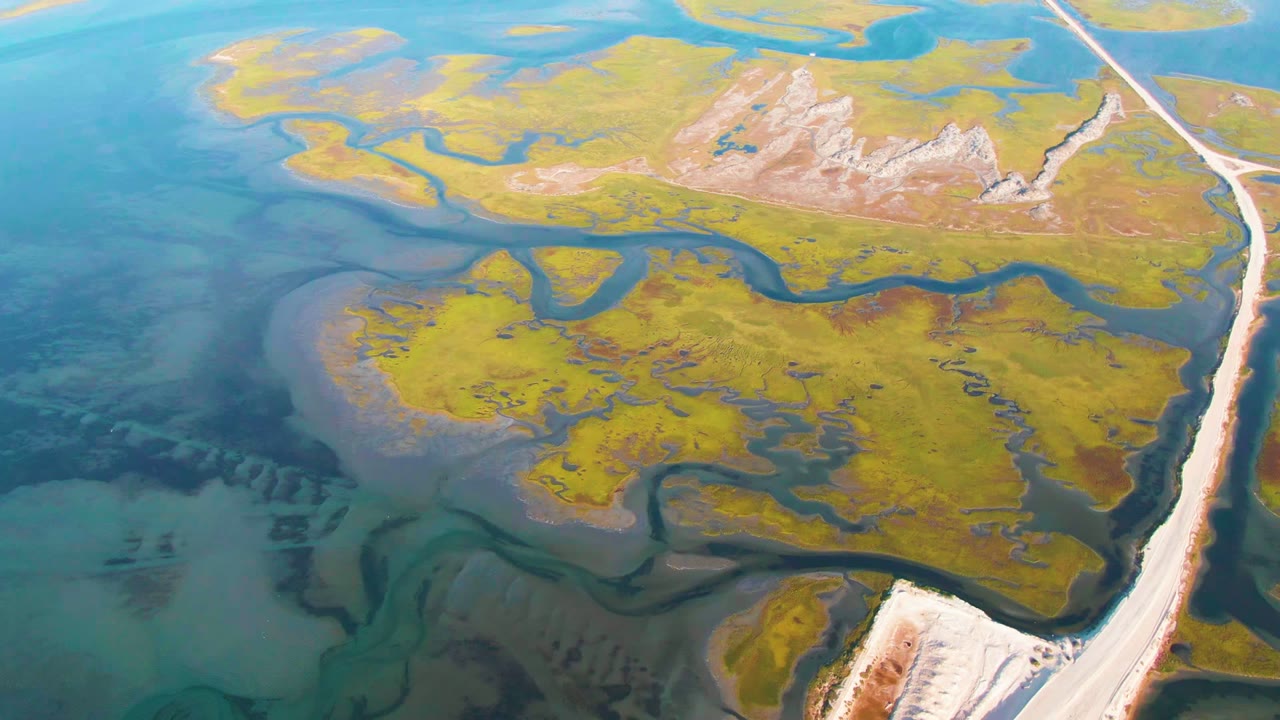 Wetland islands and channels beside a long pale road