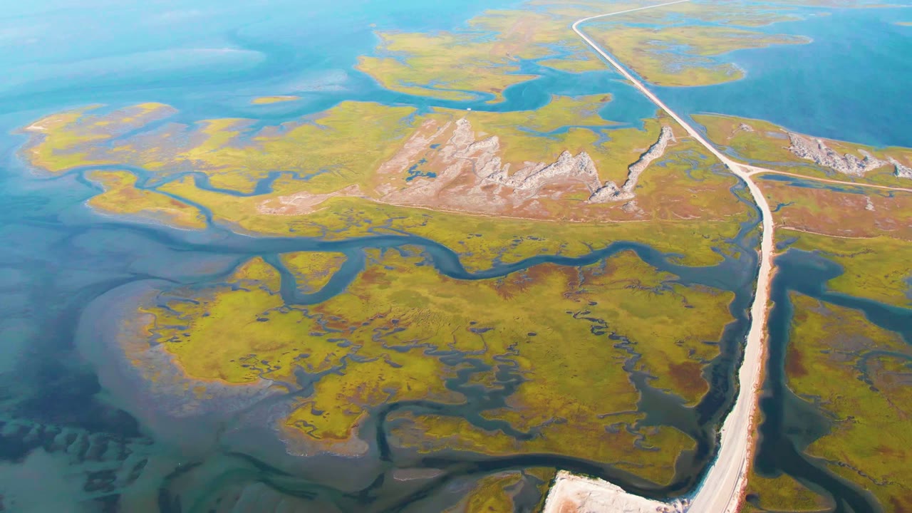 Third frame holds the Guerrero Negro wetland from above, with low rocky ridges near the center, a pale causeway to the right, and no visible people.