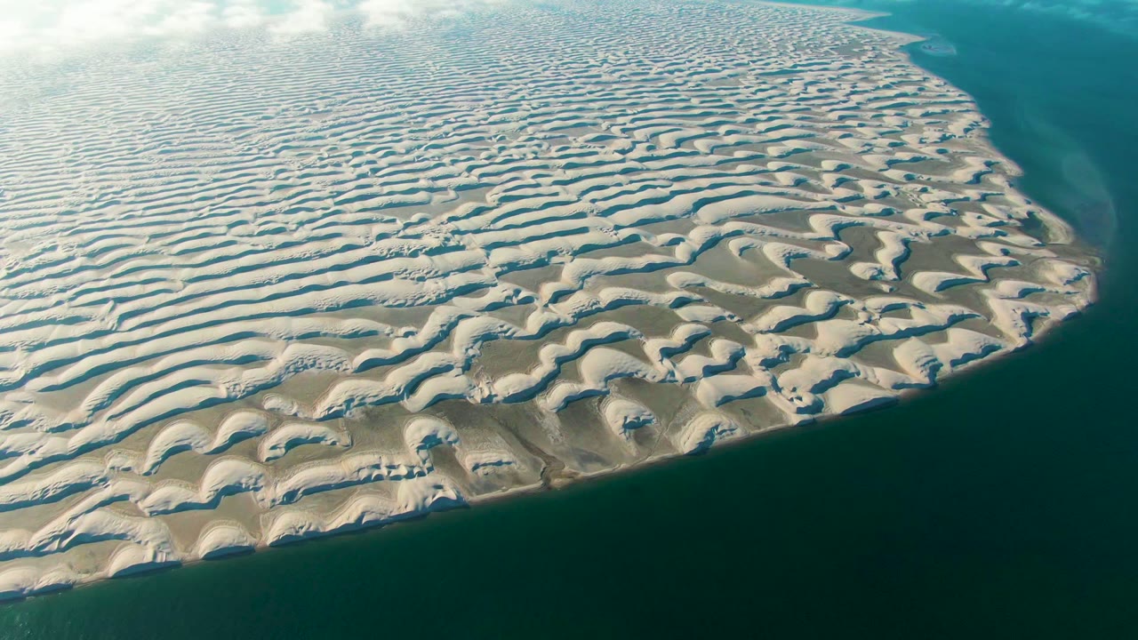 Rippled coastal sand stretches toward a narrow band of ocean.